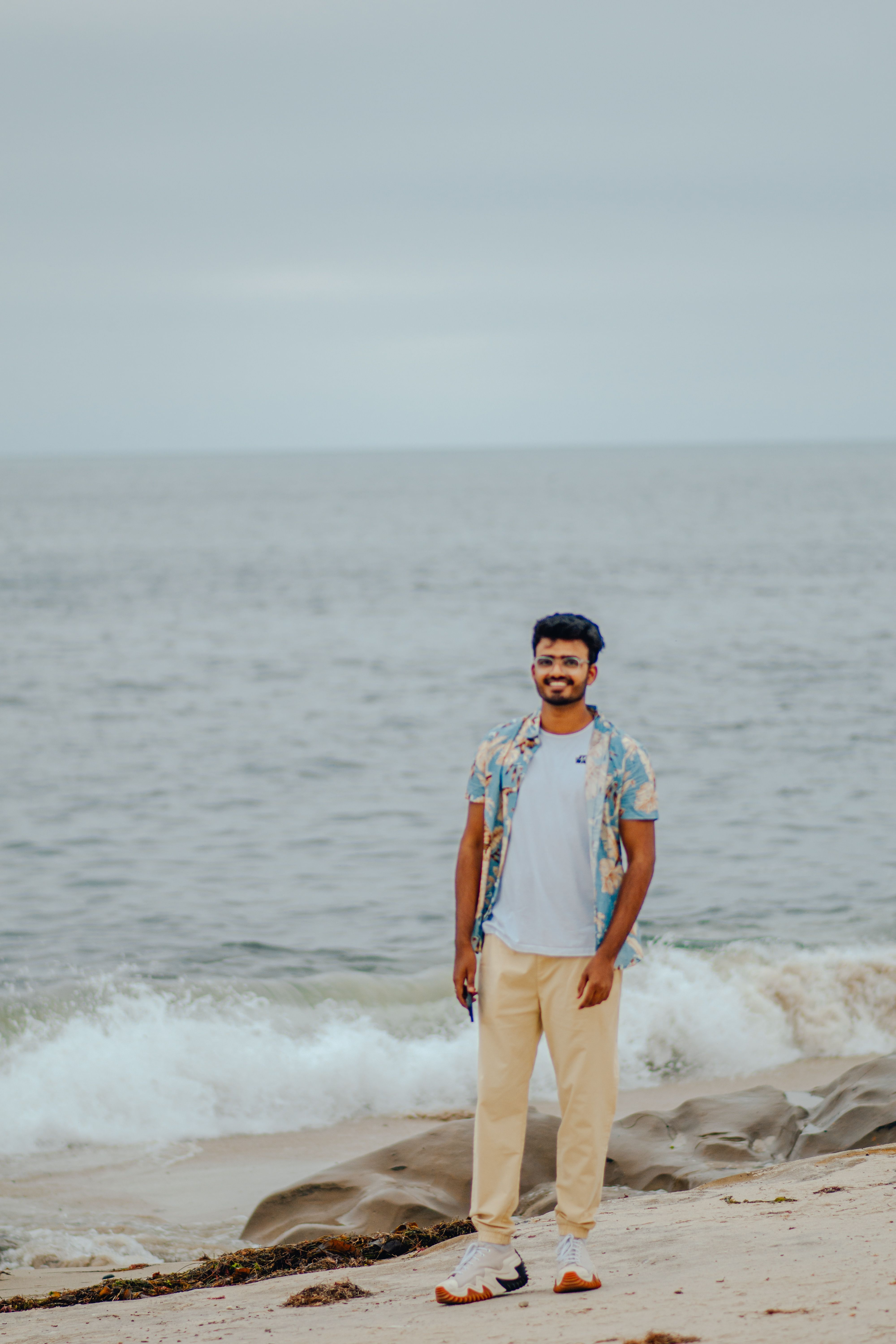 Casual portrait of a man standing on a beach in San Diego with the ocean in the background.