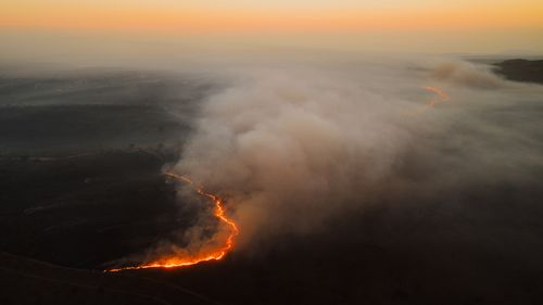 Free Dramatic aerial shot of a forest fire spreading with smoke at sunset in South Africa. Stock Photo