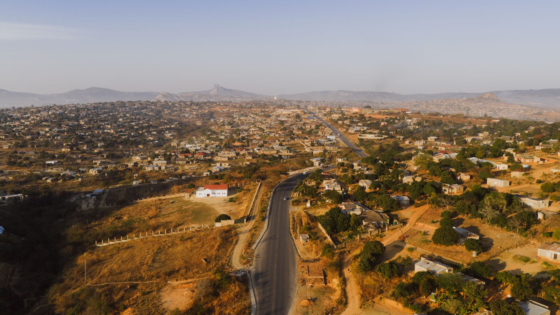 Aerial panorama of Phola township showcasing sunlit houses, roads, and hills in South Africa.