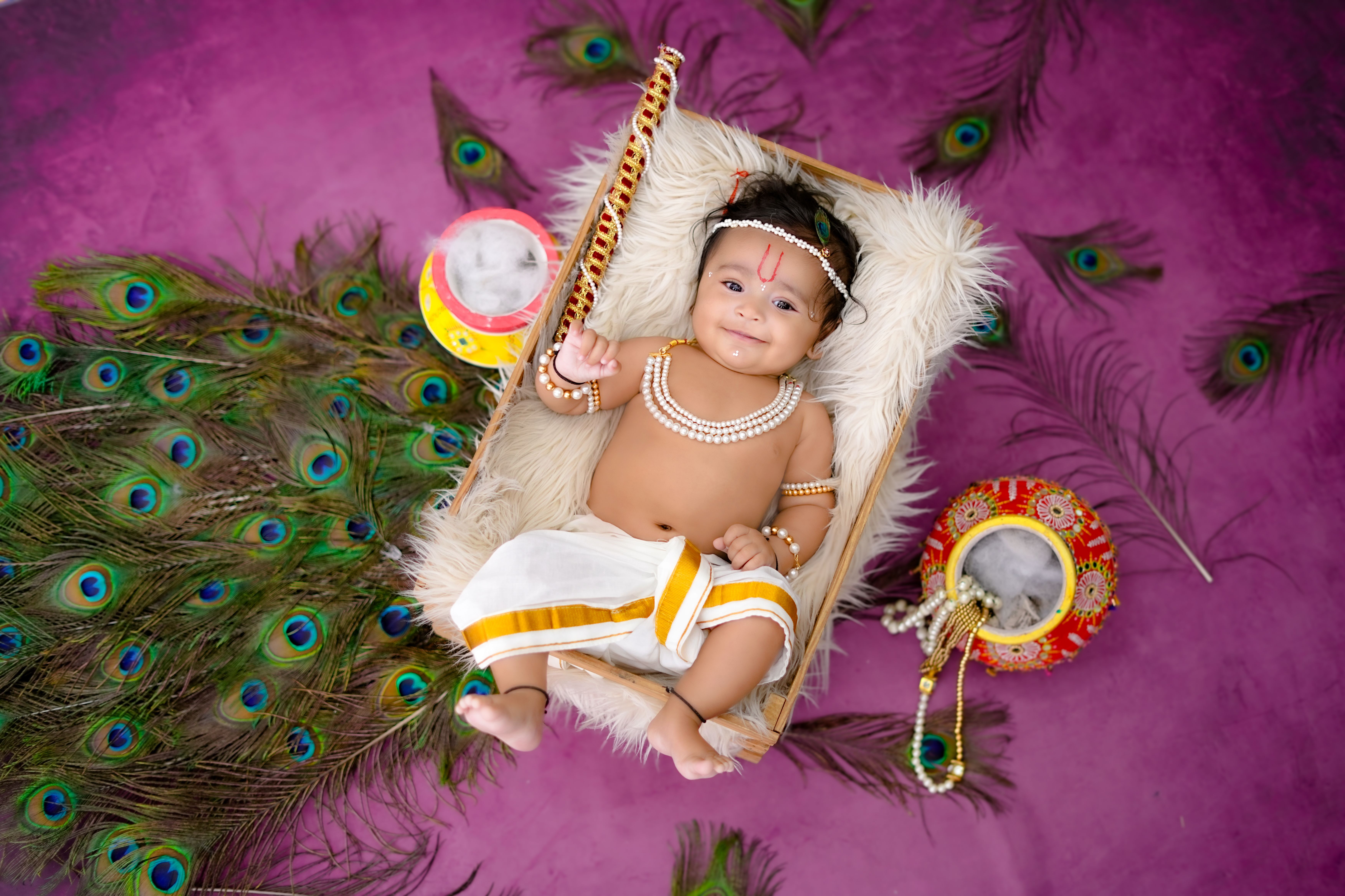 Charming baby in traditional Indian attire with peacock feathers, celebrating cultural heritage.