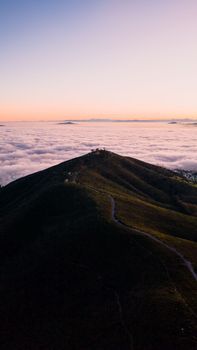 A stunning aerial view of a mountain peak above Cape Town, South Africa during sunset with a sea of clouds underneath.