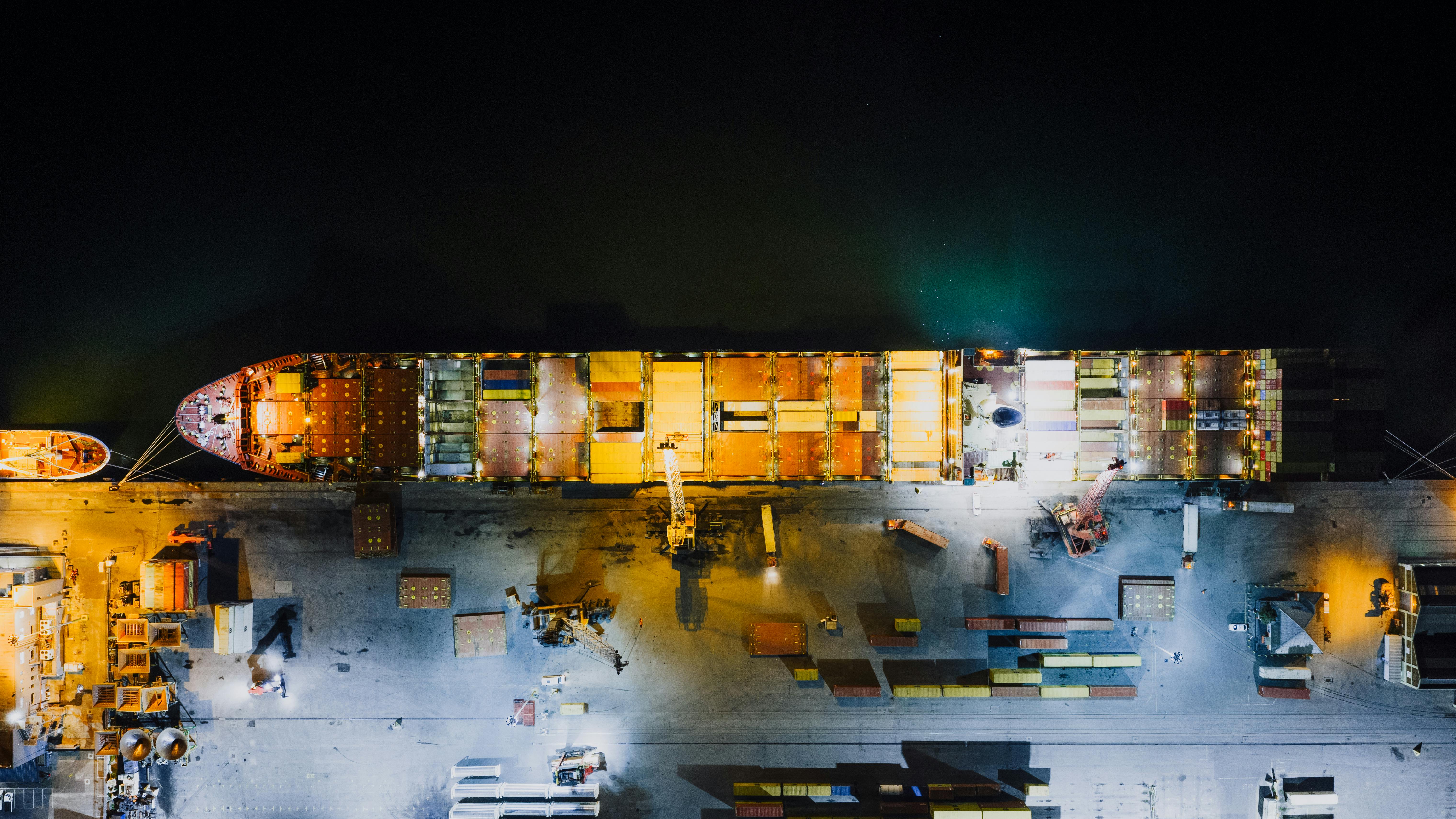 Top-down view of a cargo ship docked at Cape Town harbor at night, highlighting industrial maritime 