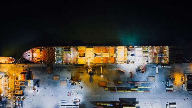 Top-down view of a cargo ship docked at Cape Town harbor at night, highlighting industrial maritime operations.
