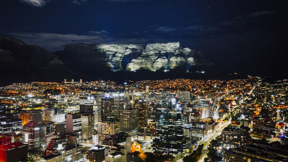 Amazing Cape Town: 25min Helicopter Flight with Complimentary Boat Cruise Review Review 2026 - Stunning aerial view of Cape Town's illuminated cityscape with Table Mountain in the background at night.