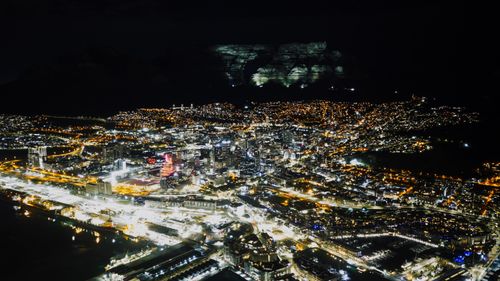Free Stunning night aerial view of Cape Town city lights with majestic Table Mountain in the background. Stock Photo