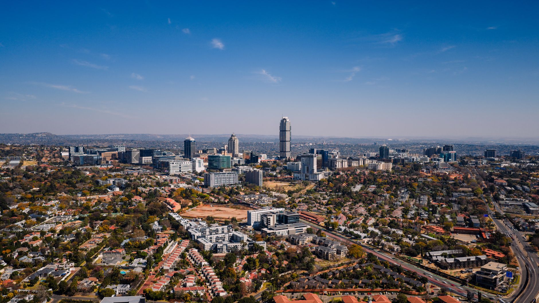 Aerial shot capturing the bustling urban skyline of Sandton in Gauteng, with its mix of modern skyscrapers and suburban areas.