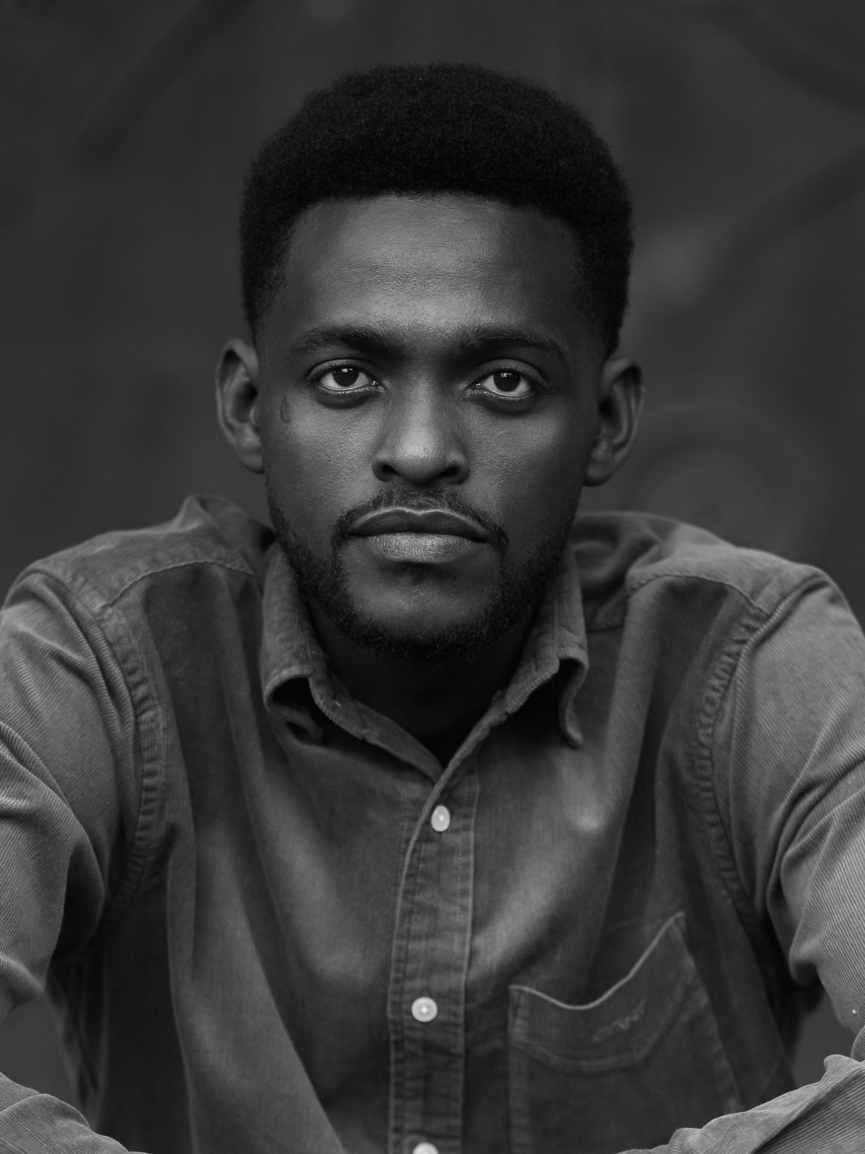Black and white portrait of a confident young man in a denim shirt, creating a classic and artistic vibe.