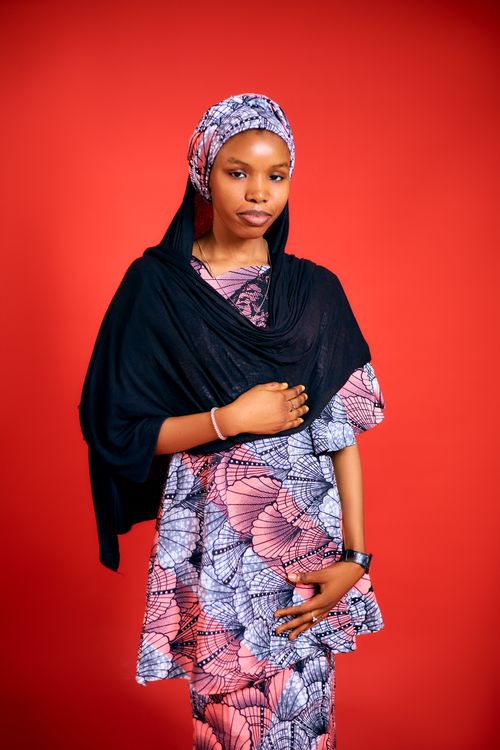 Free Stylish young woman in traditional attire poses confidently against a red background. Stock Photo