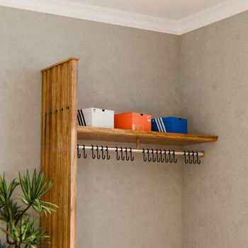 Wooden coat rack with hooks and shoe boxes on shelf in a modern interior.