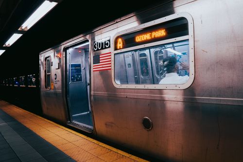 Free Photo of a subway train at a New York City station at night featuring the American flag and Ozone Park sign. Stock Photo