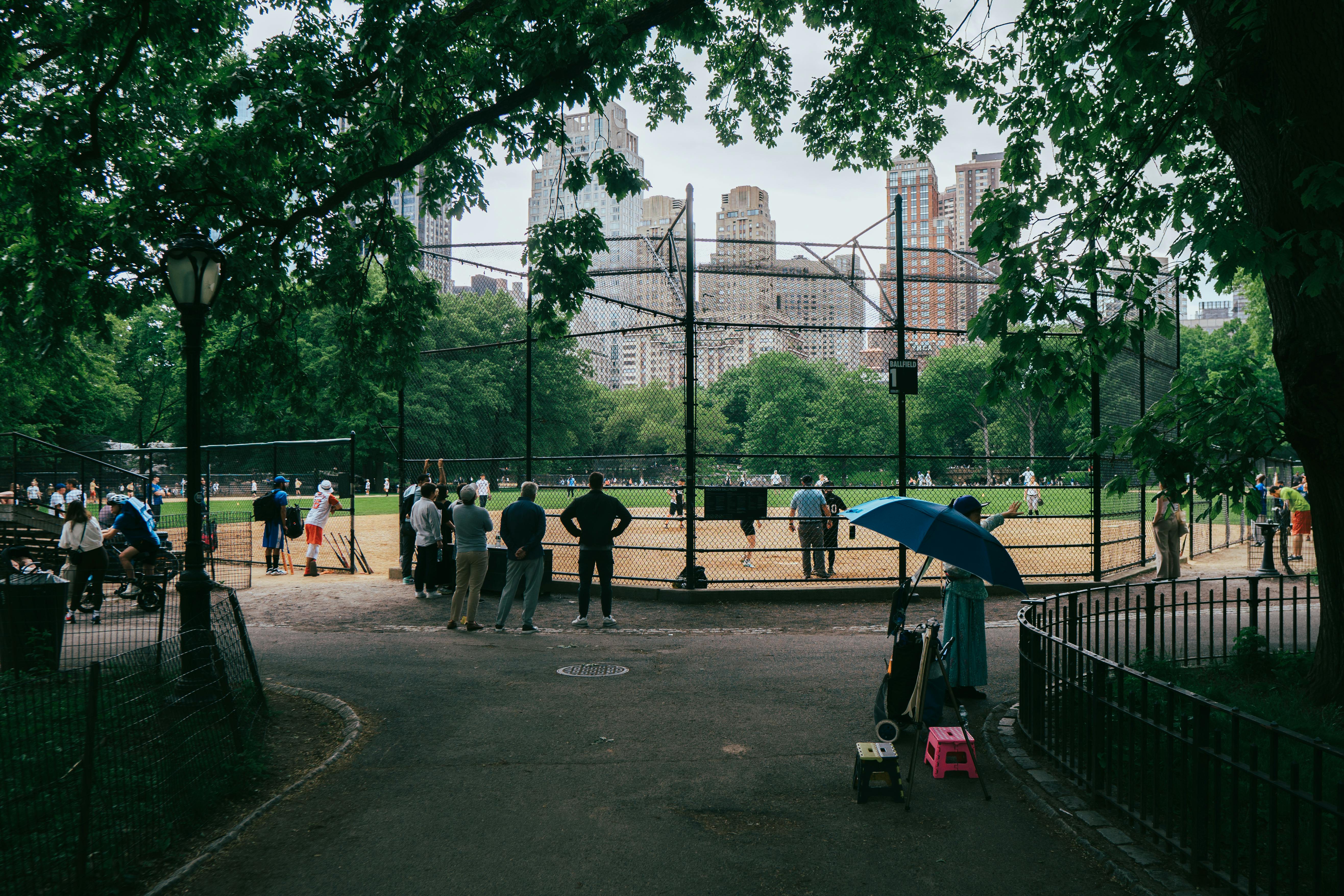 A baseball game in Central Park with Manhattan skyscrapers in the background.