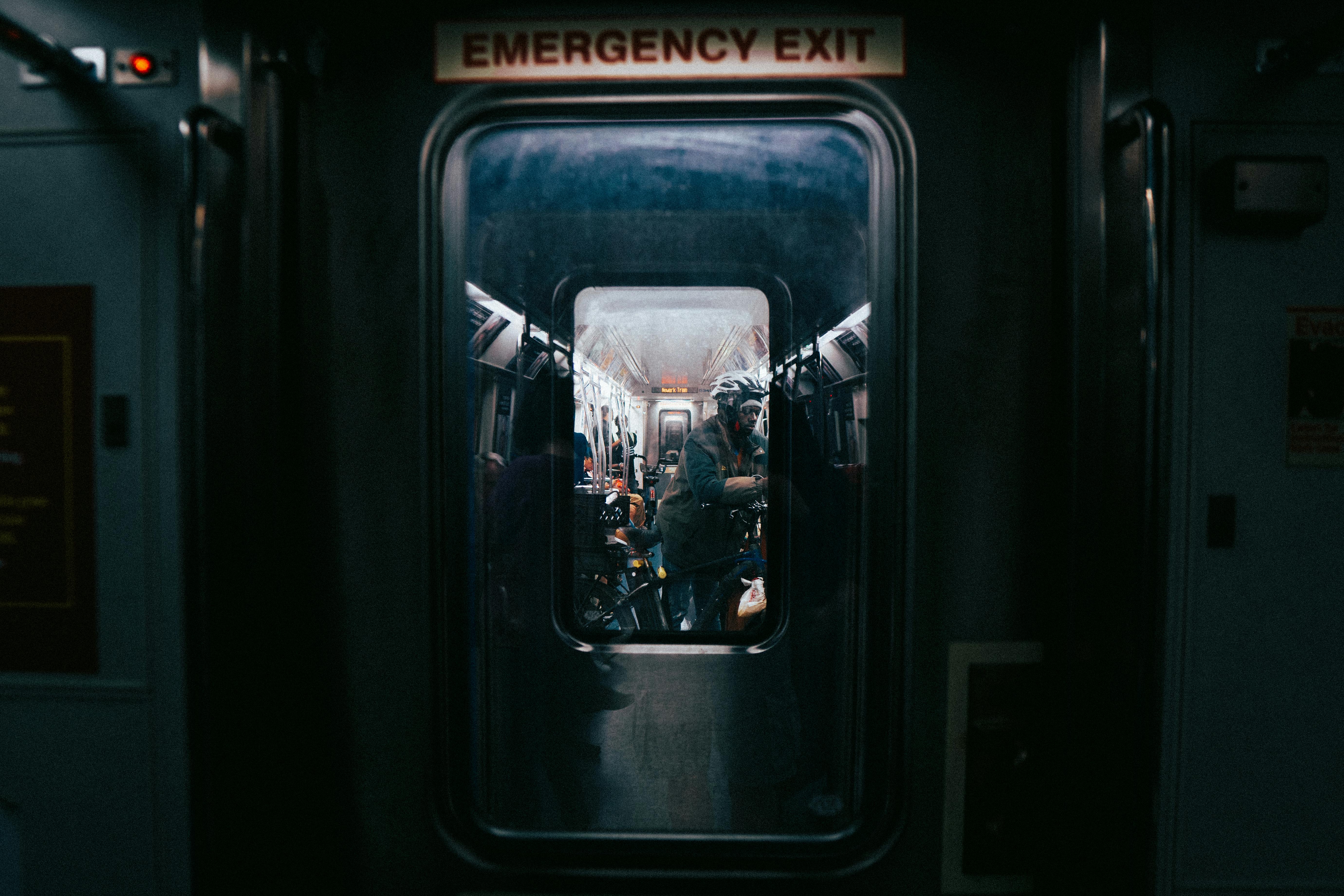 A view through an emergency exit in a New York subway, capturing passengers inside.