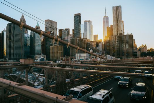 Captivating sunset view of Manhattan skyscrapers from the iconic Brooklyn Bridge in New York City.
