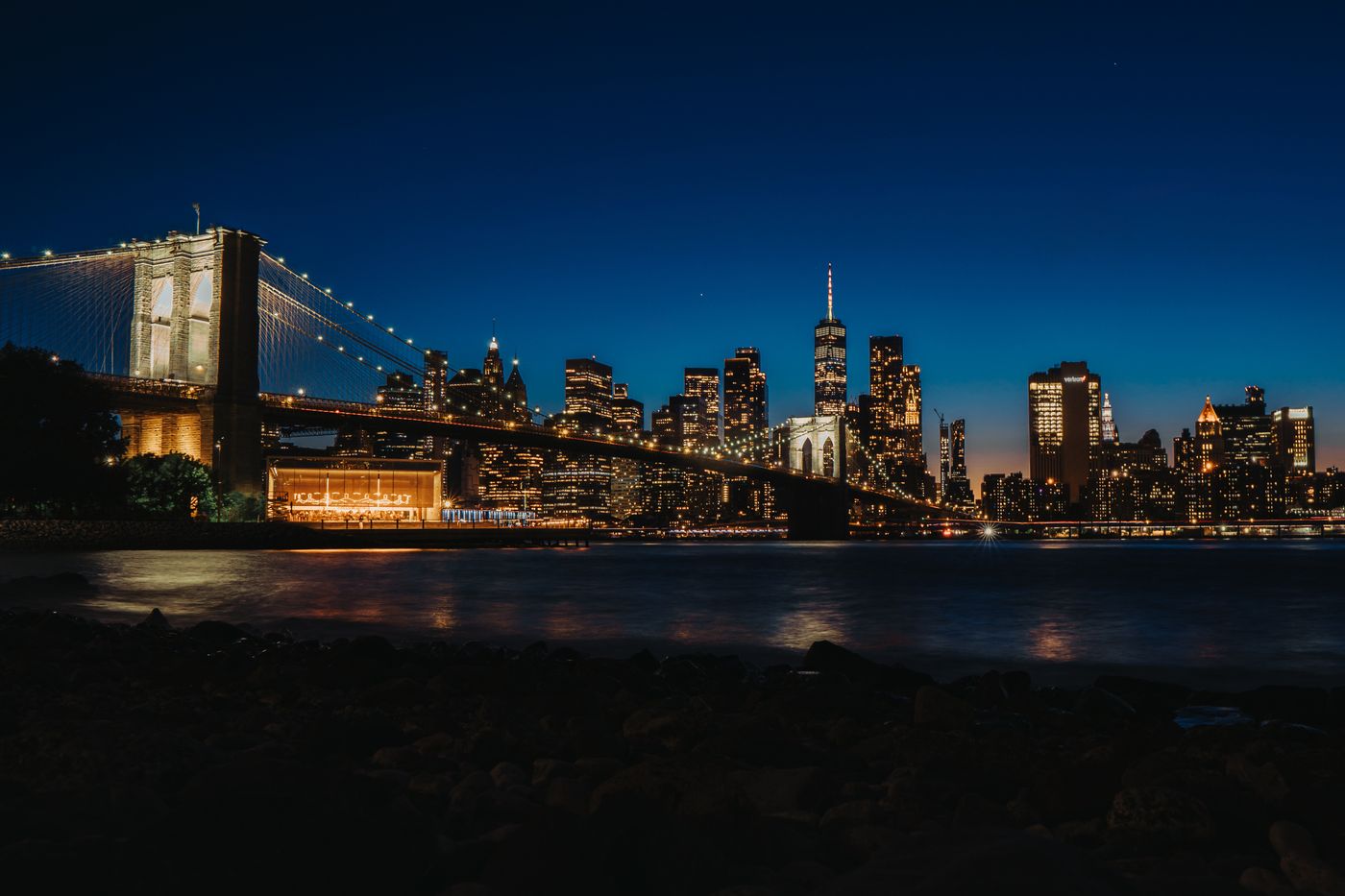 New York City skyline at night with the Brooklyn Bridge and illuminated skyscrapers