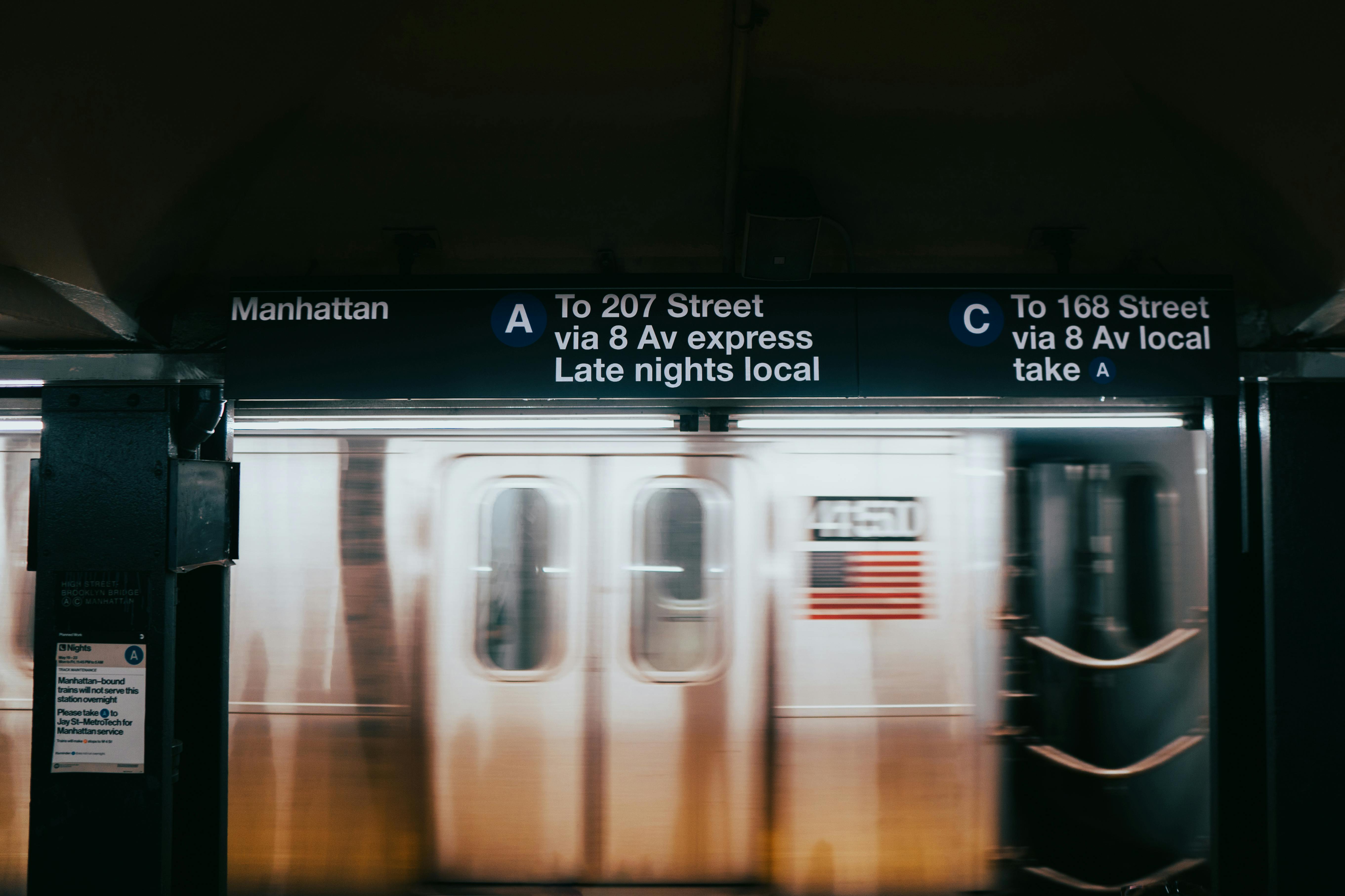 A blurred image of a subway train passing through Manhattan's station in New York City at night.