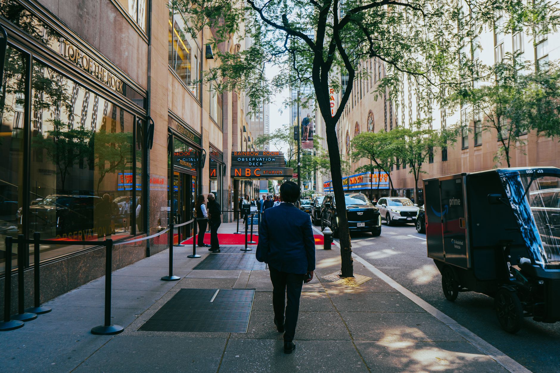 Busy street scene near Rockefeller Center in New York City, showcasing modern architecture and lively urban life.
