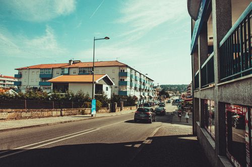 Free View of a sunny street with buildings and parked cars, typical of a Mediterranean town. Stock Photo