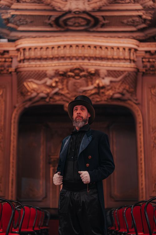 Free A man in a Victorian costume stands in an opulent room with rich decoration, showcasing classic fashion. Stock Photo