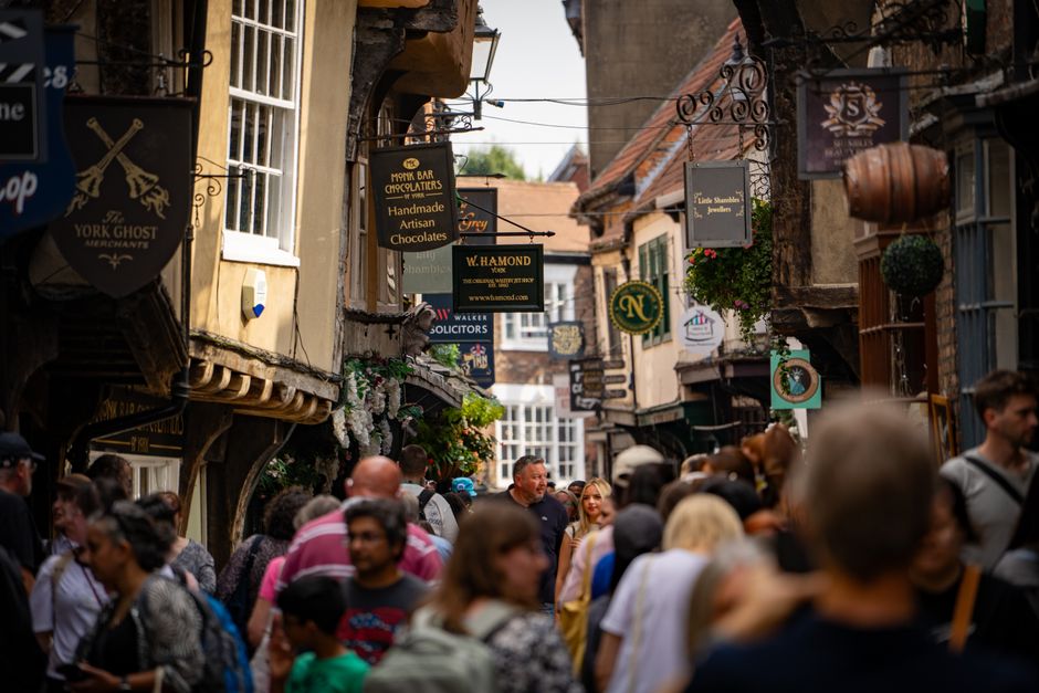 Explore the vibrant and historic Shambles street in York, filled with lively crowds and charming shop signs.