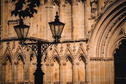 Historic York Minster facade with vintage lamp post casting shadows. Captivating Gothic details.