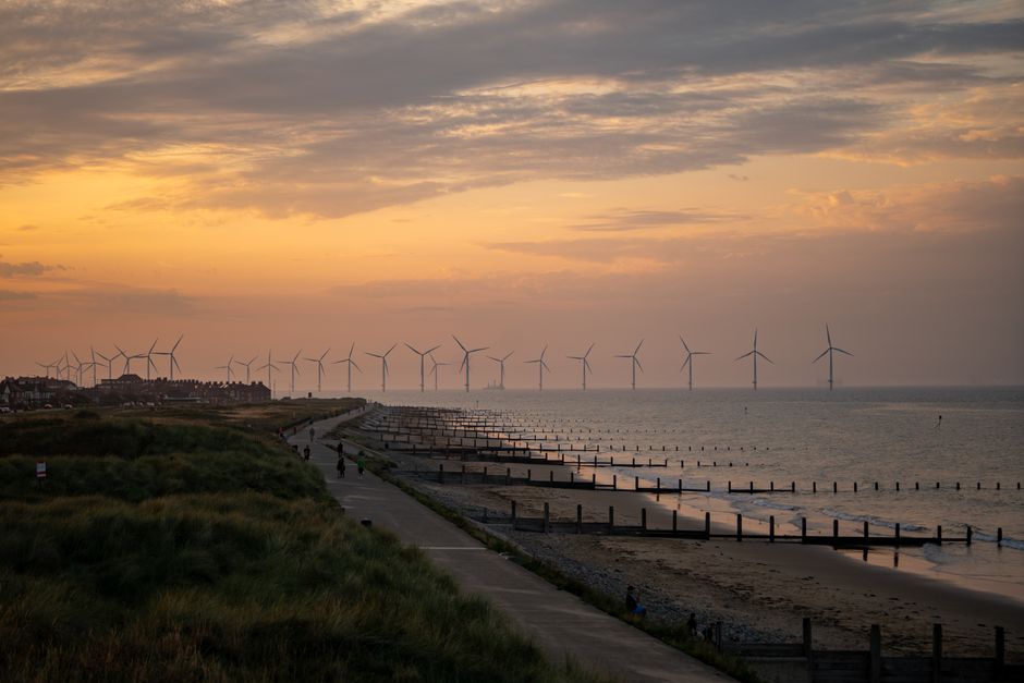 Beautiful seaside view of York, England with wind turbines and a vibrant sunset sky.