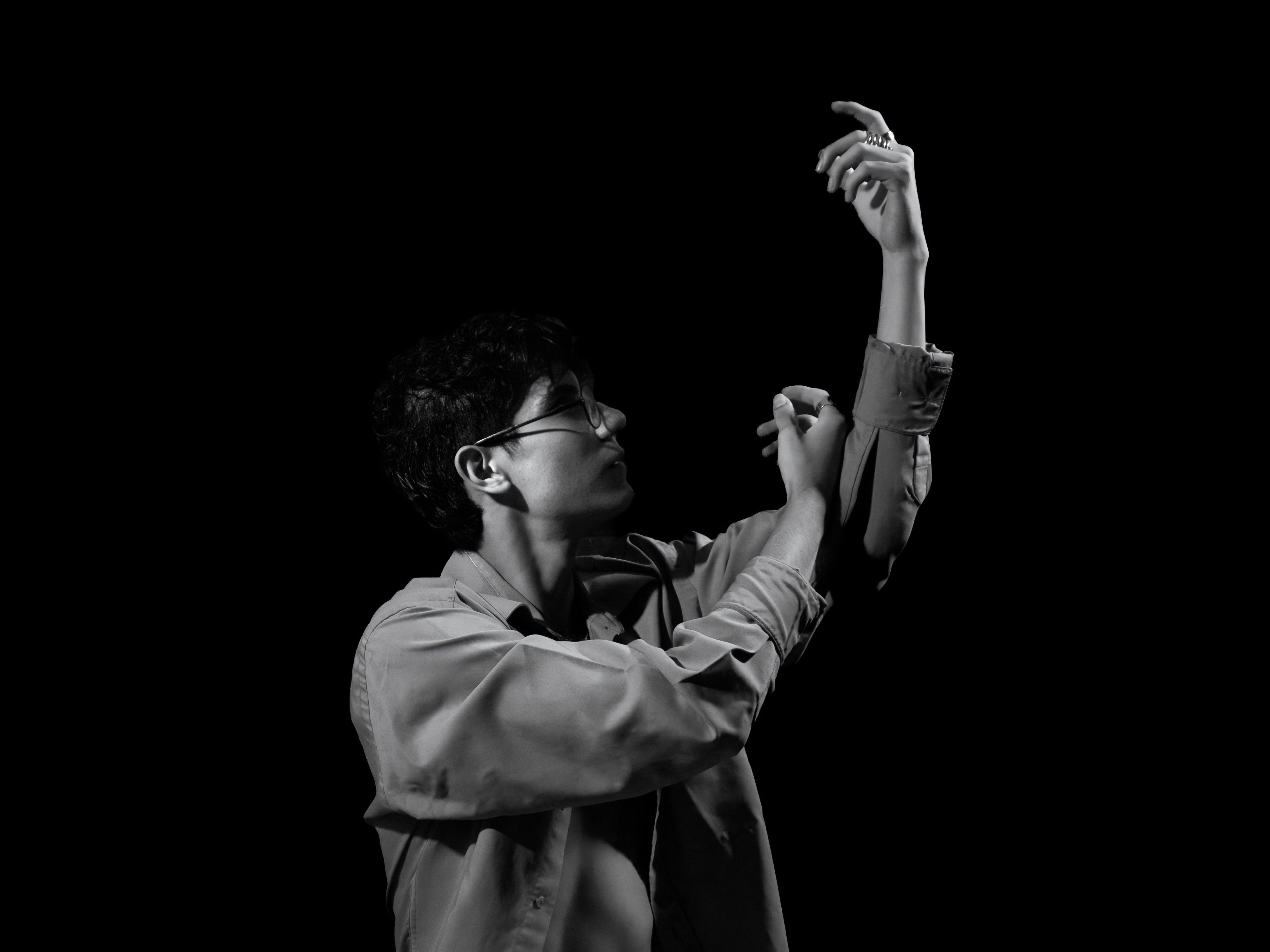 Artistic black and white portrait of a man adjusting his sleeves, creating a dramatic mood.