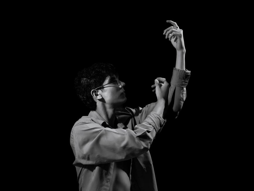Artistic black and white portrait of a man adjusting his sleeves, creating a dramatic mood.