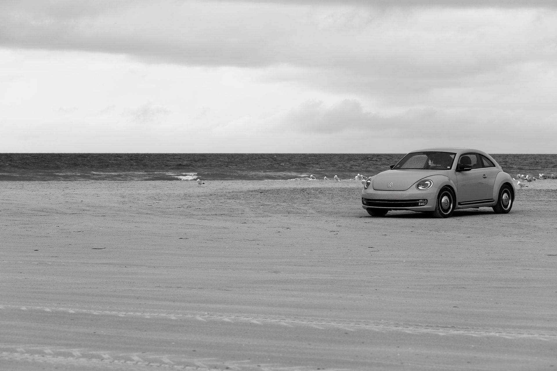 A vintage VW Beetle parked on a serene Danish beach by the North Sea.