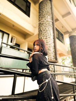 Stylish woman in black outfit posing outdoors, Bandung, Indonesia.