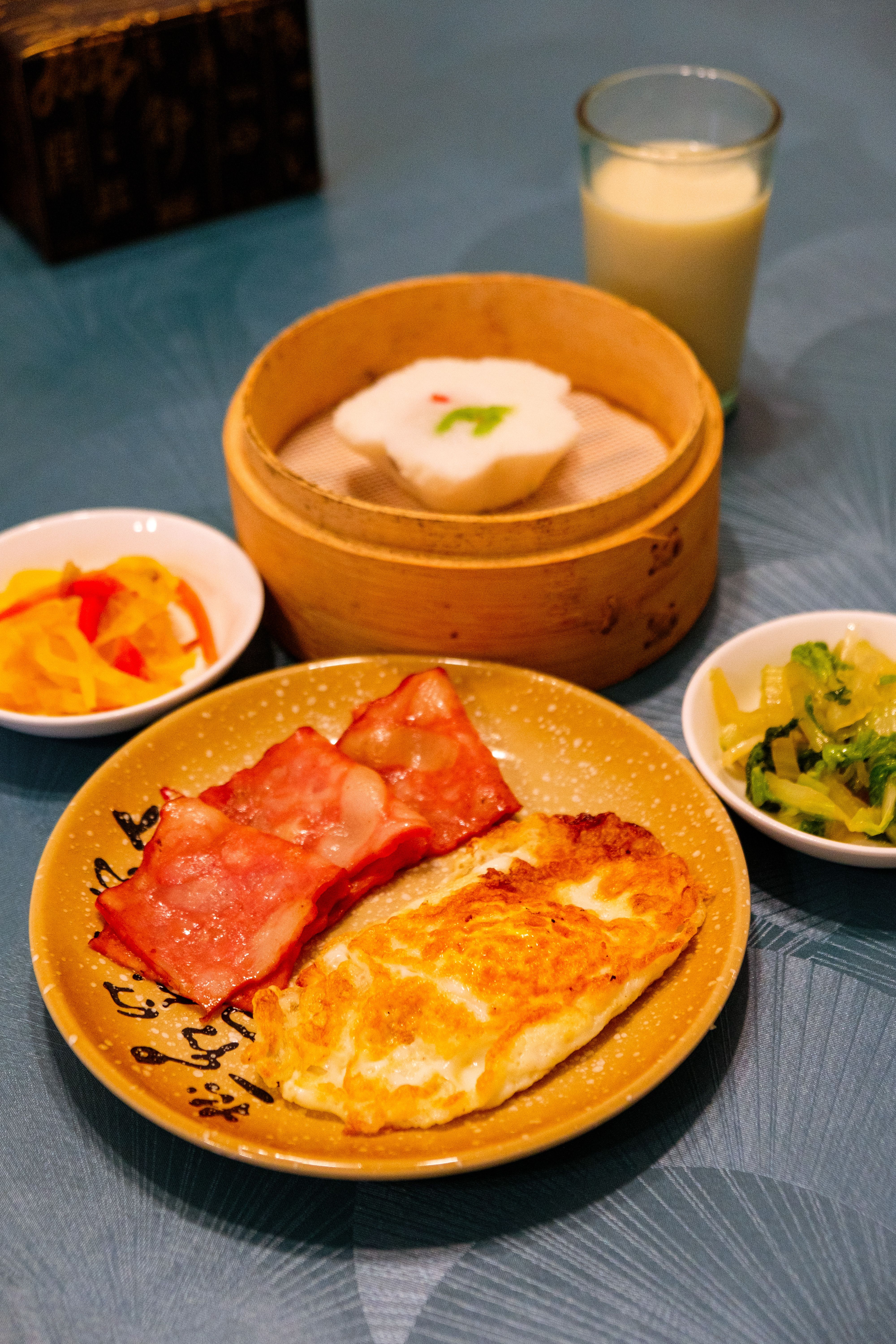 Inviting Asian breakfast featuring dim sum, omelet, ham, and veggies, creating a savory start to the day.