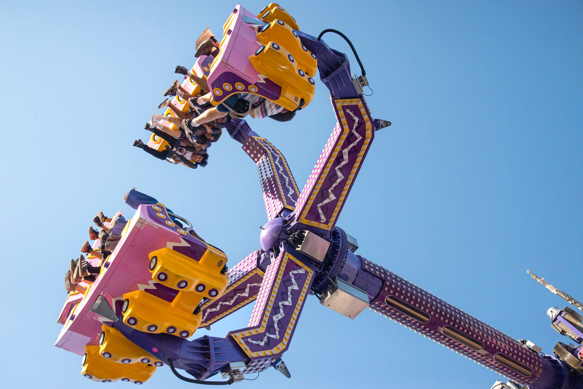 Exciting action shot of a carnival ride with people enjoying a sunny day adventure.