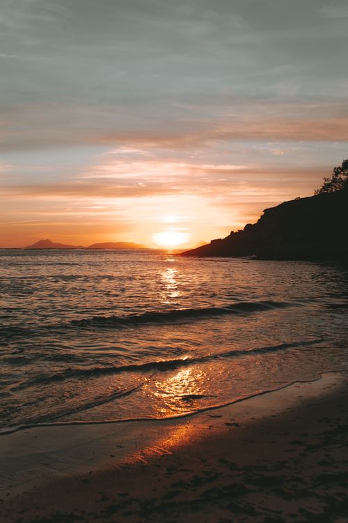 Free Peaceful sunset at the beach with gentle waves and warm hues, perfect for relaxation. Stock Photo