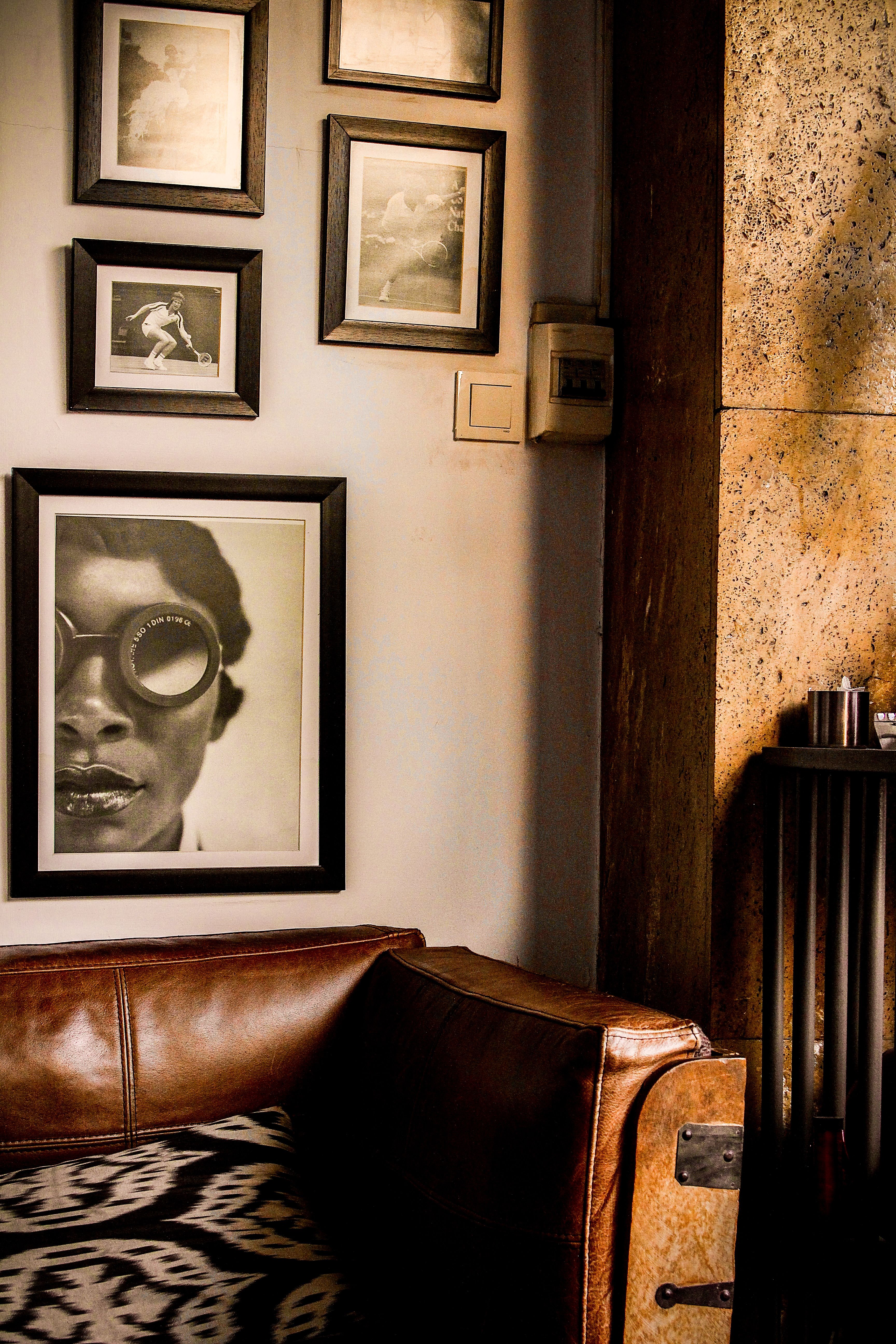 Vintage-styled interior with leather couch and framed artwork on a textured wall.