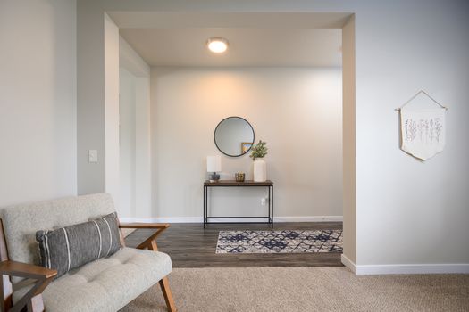 Stylish living room with minimalist decor, featuring a comfortable chair, wall art, and subtle lighting.