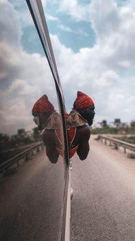 A traveler peers from a vehicle on a highway in Accra, Ghana, captured with a reflective view.