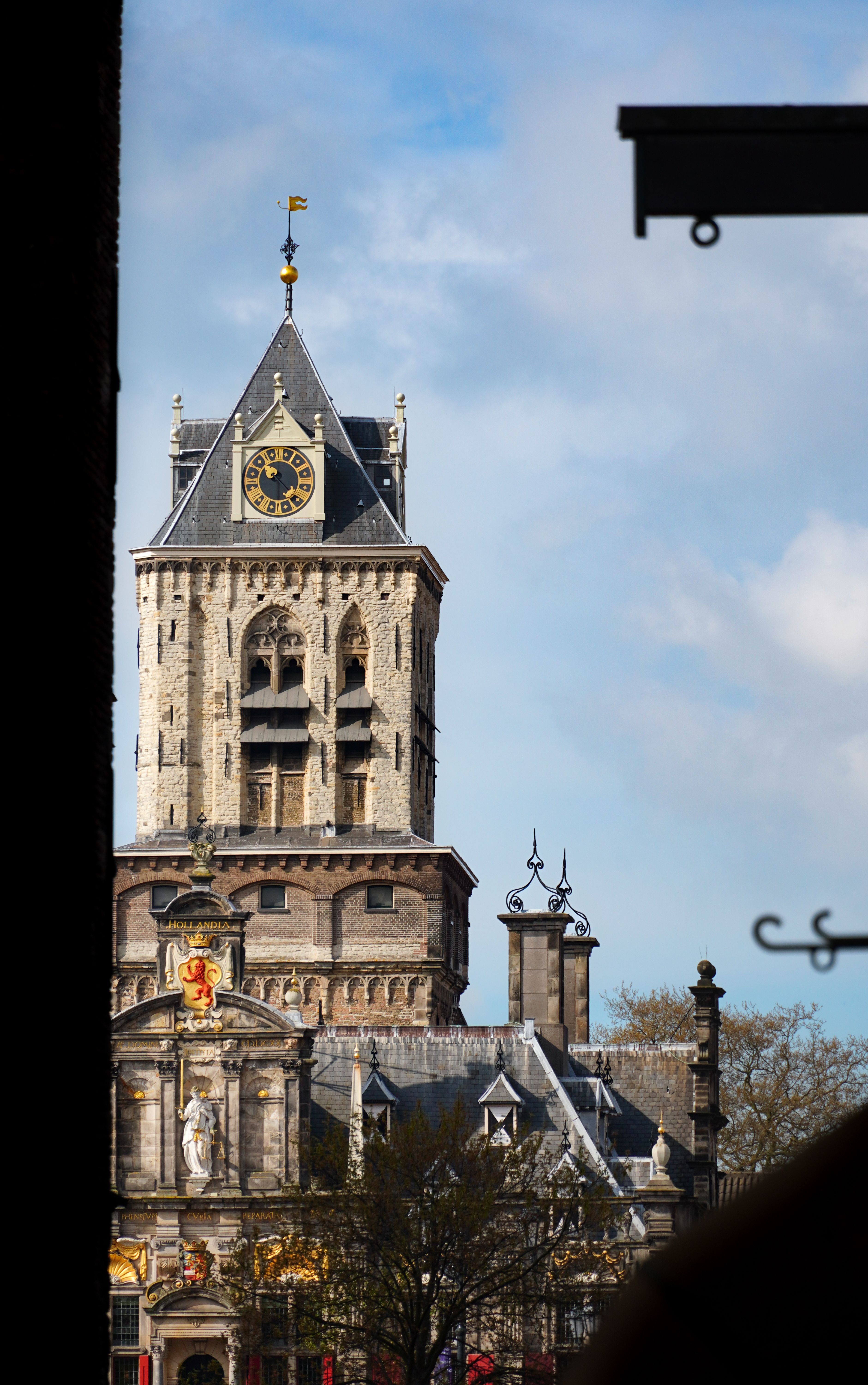 The historic Nieuwe Kerk clock tower in Delft, Netherlands, under a clear blue sky.