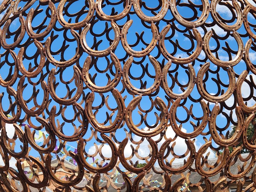 A stunning display of interconnected rusty horseshoes creating a circular pattern against a clear blue sky.