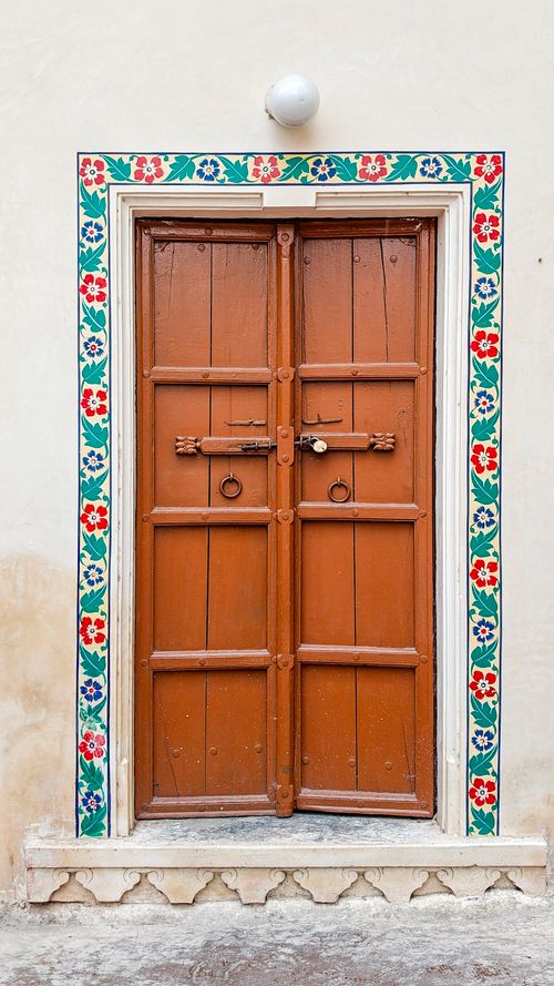 Free A traditional wooden door in Udaipur, India, framed by colorful floral designs, showcasing Indian architecture. Stock Photo