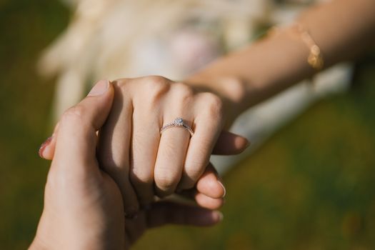 Close-up of hands with an engagement ring, symbolizing love and commitment.