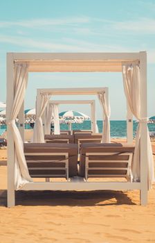 Elegant beach cabana setup on a sandy Venetian beach with a stunning sea view.