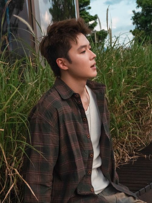 Free Young man in casual attire sitting outdoors amidst greenery in Shenzhen, China. Stock Photo