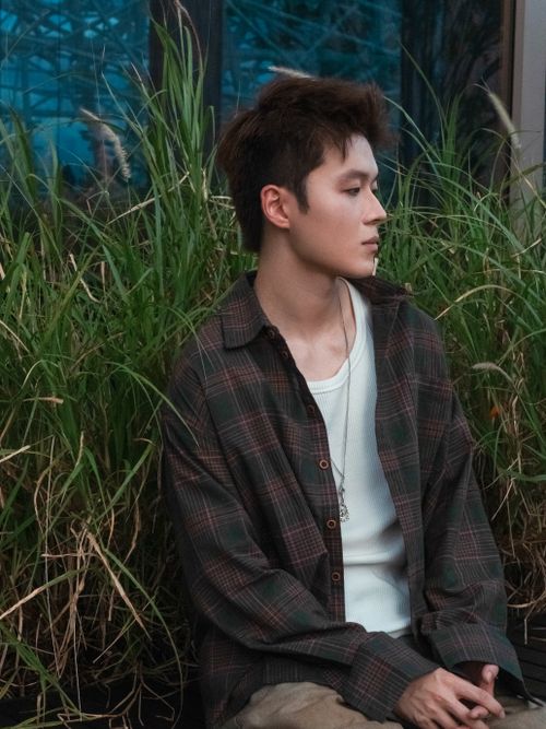 Free Thoughtful young man sitting outdoors surrounded by greenery in Shenzhen. Stock Photo
