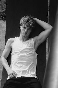 Striking black and white portrait of a young man confidently posing outdoors.