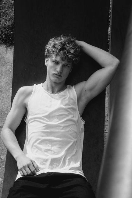 Striking black and white portrait of a young man confidently posing outdoors.