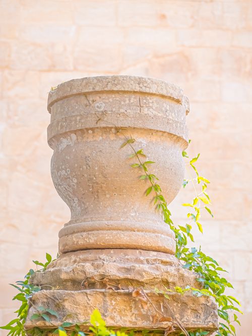 Free Close-up of a rustic stone pedestal wrapped in lush green ivy outdoors. Stock Photo