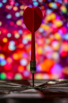 Red dart striking bullseye with vibrant bokeh backdrop, symbolizing precision and focus.