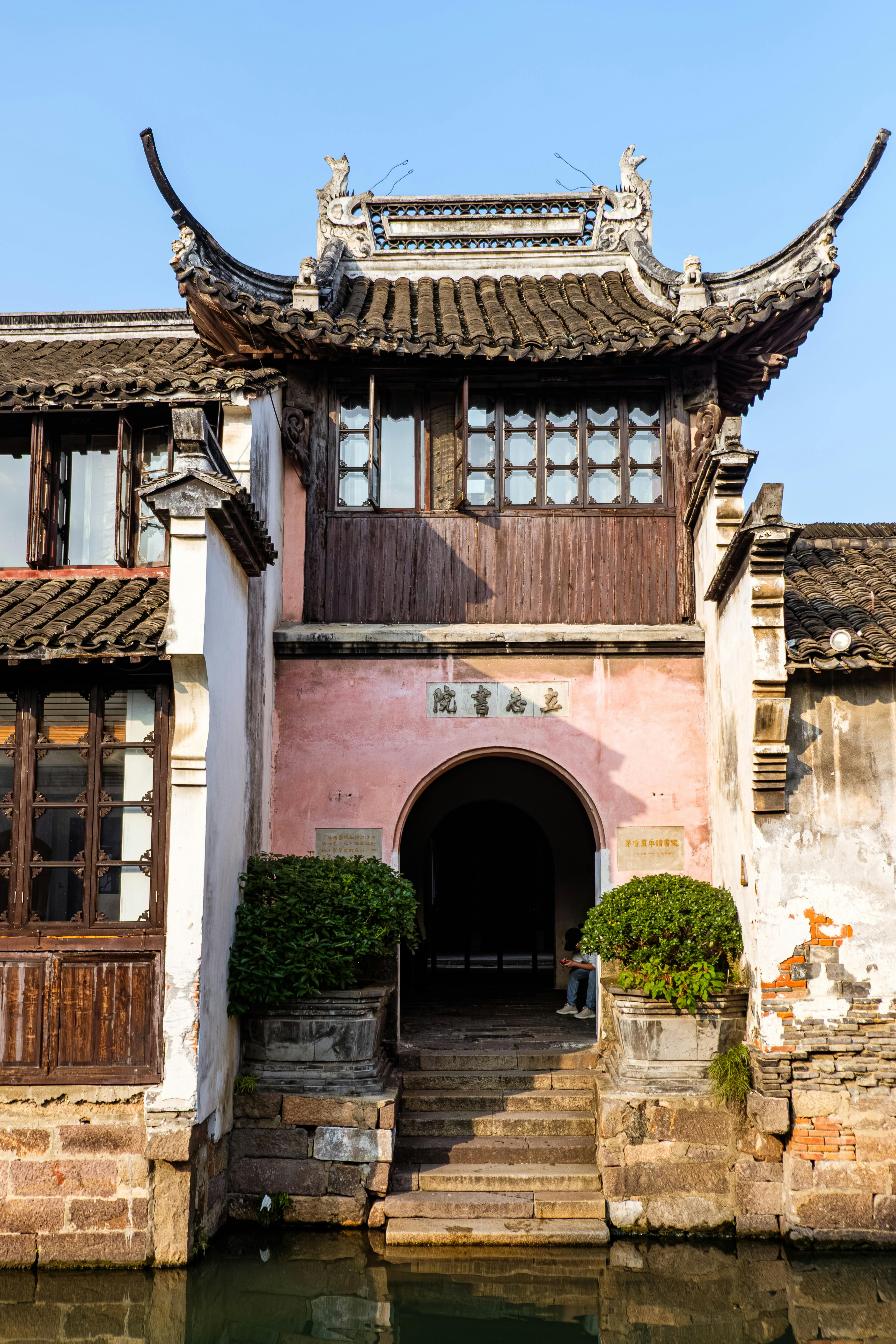 Traditional Chinese architecture in a serene water town setting with ornate roof design.