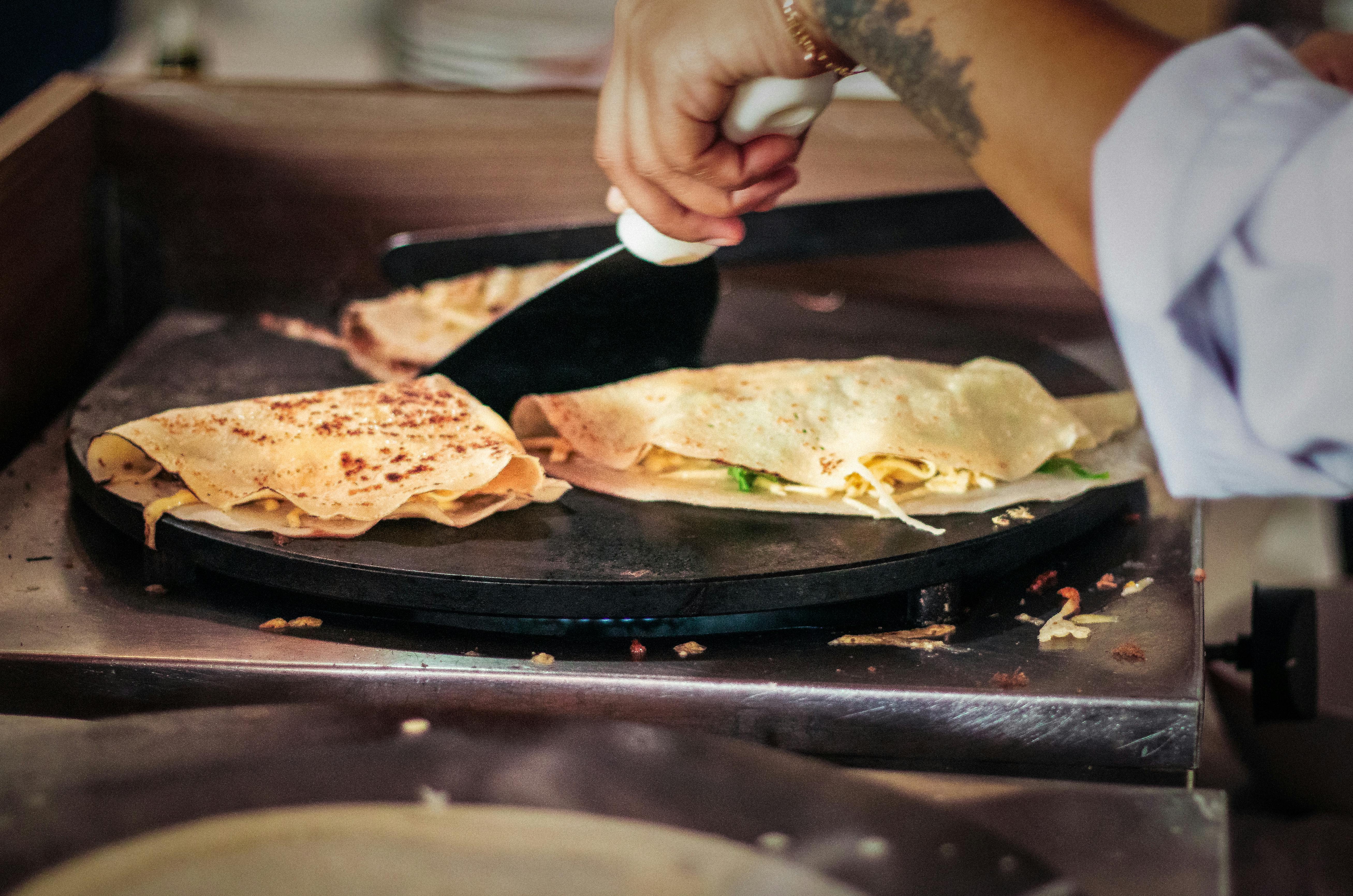 Close-up of hands cooking crepes on a hot plate at a Brazilian market. Perfect street food scene.