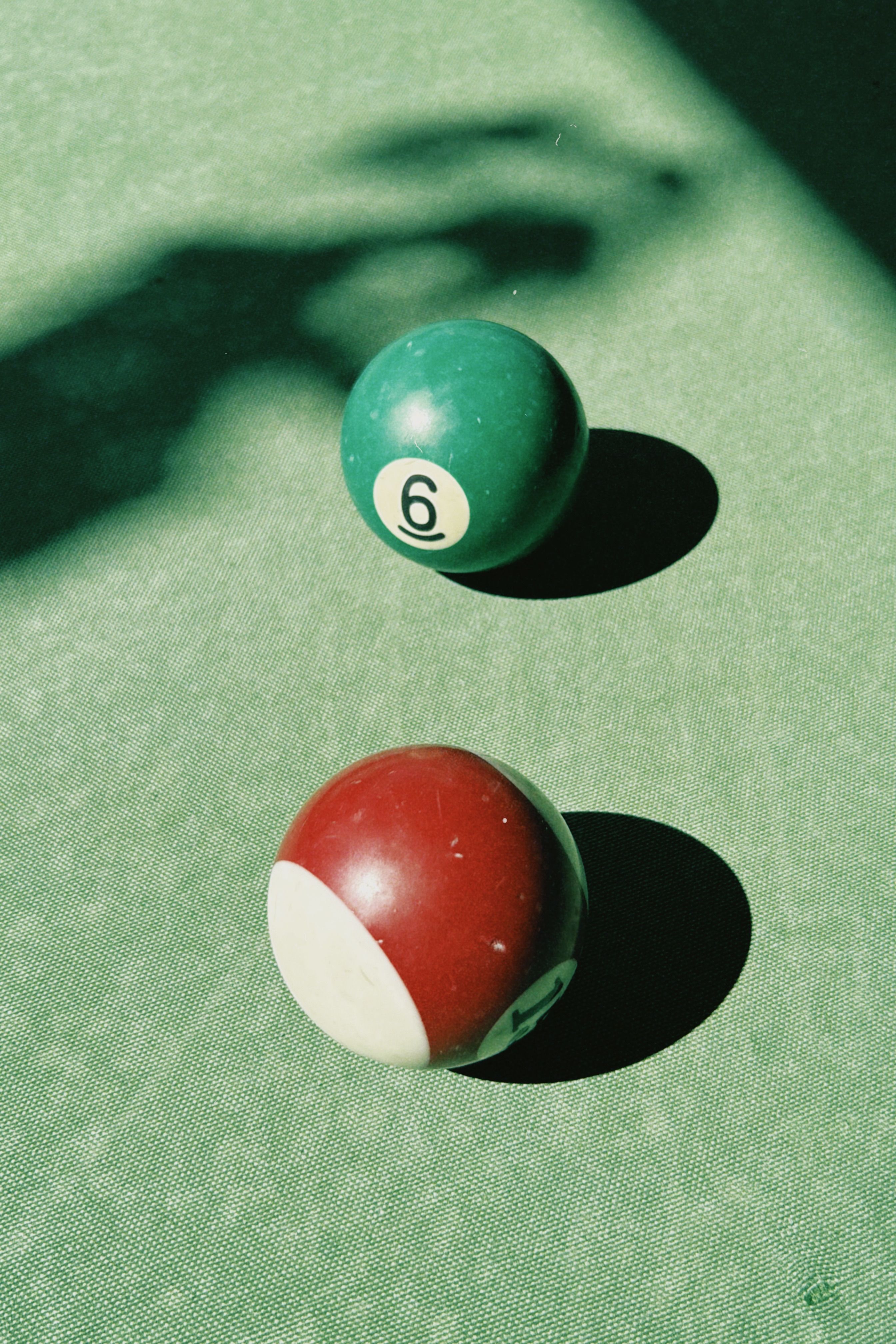 Artistic capture of billiard balls on a pool table with dramatic shadows.