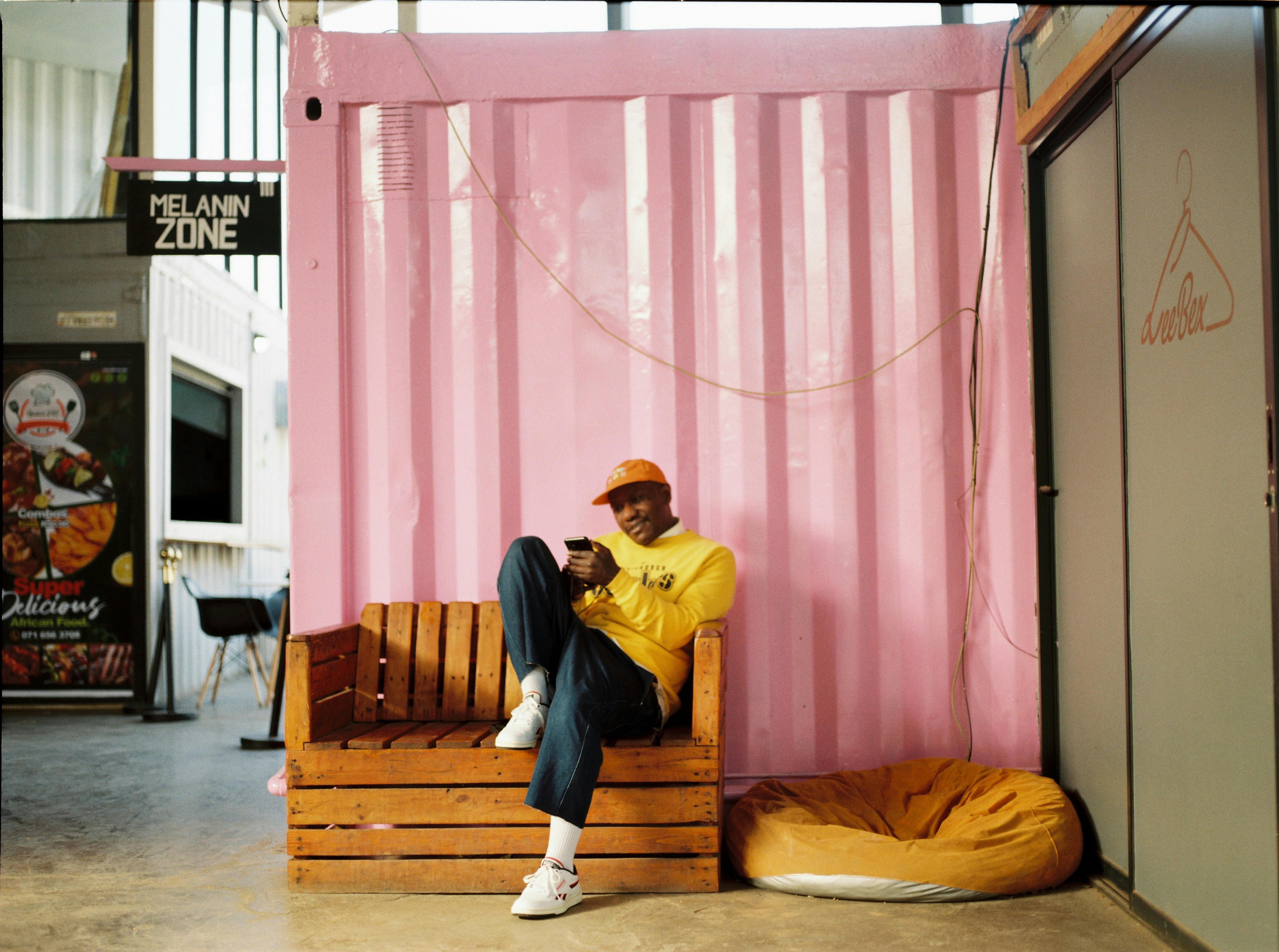 Man in casual wear relaxes on a wooden bench in a trendy indoor space.